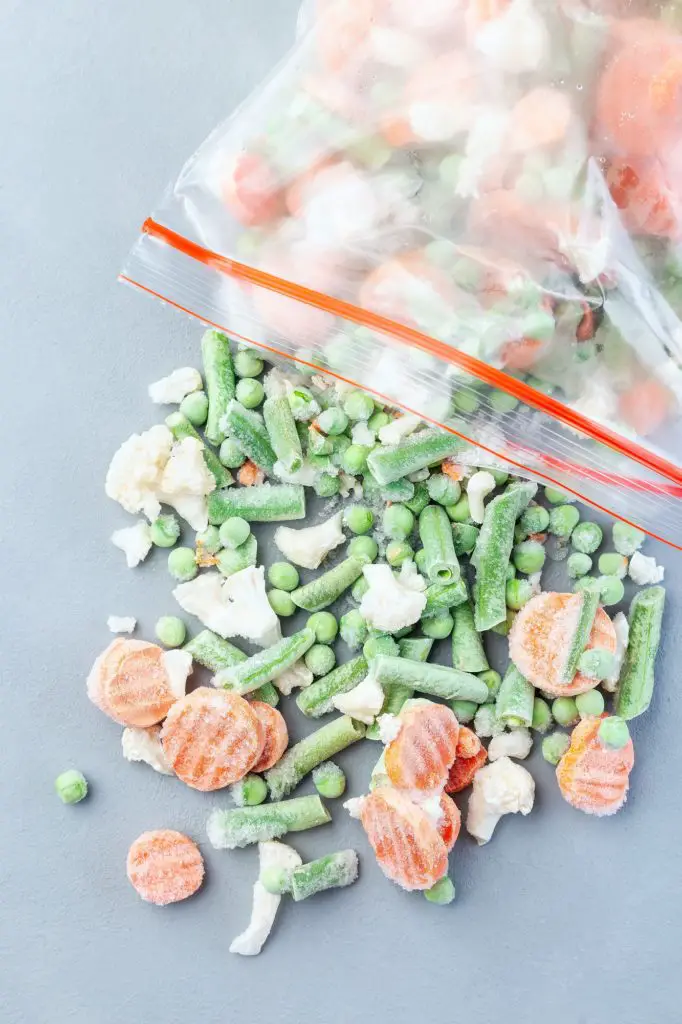 Frozen vegetables in the plastic bag and on table
