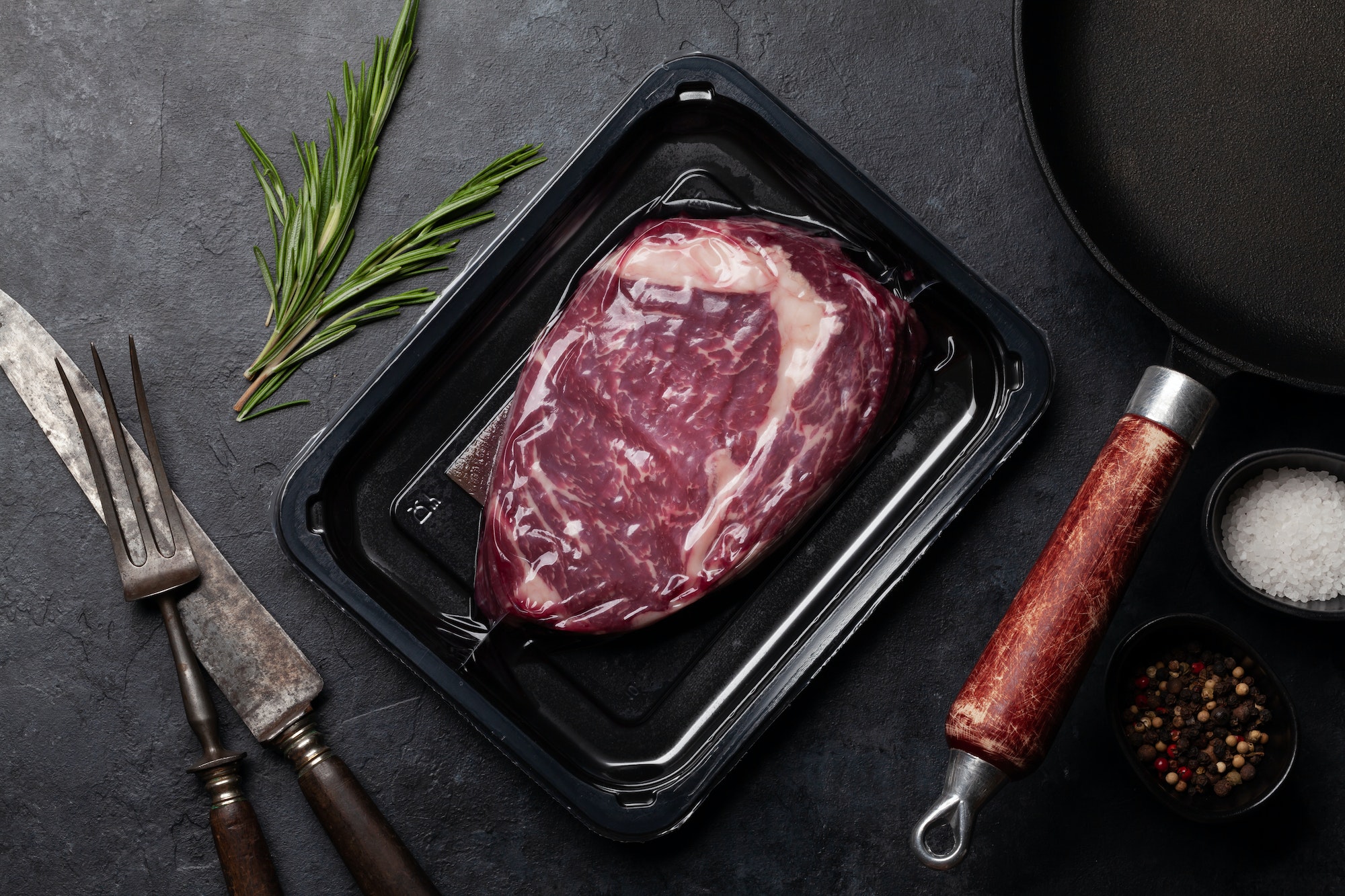 Vacuum packed beef steak. Ribeye steak and cooking utensils