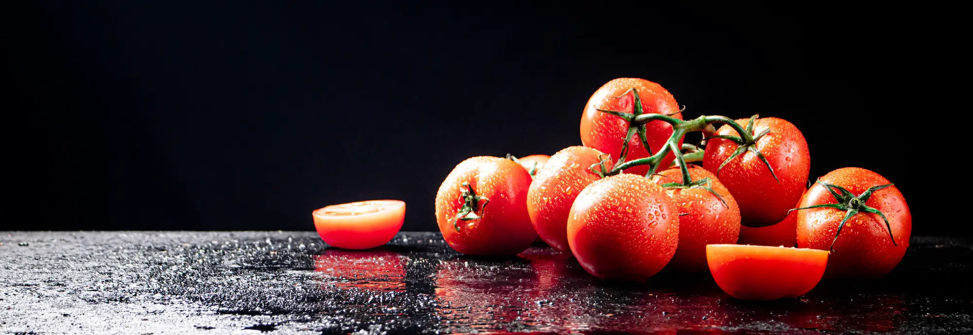 Ripe tomatoes on a branch and tomato halves.