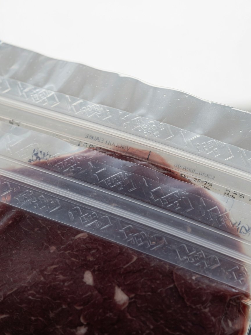 Close-up of a double heat seal strip on a vacuum sealed venison bag held up to light, showing the clean dual-weld seal
